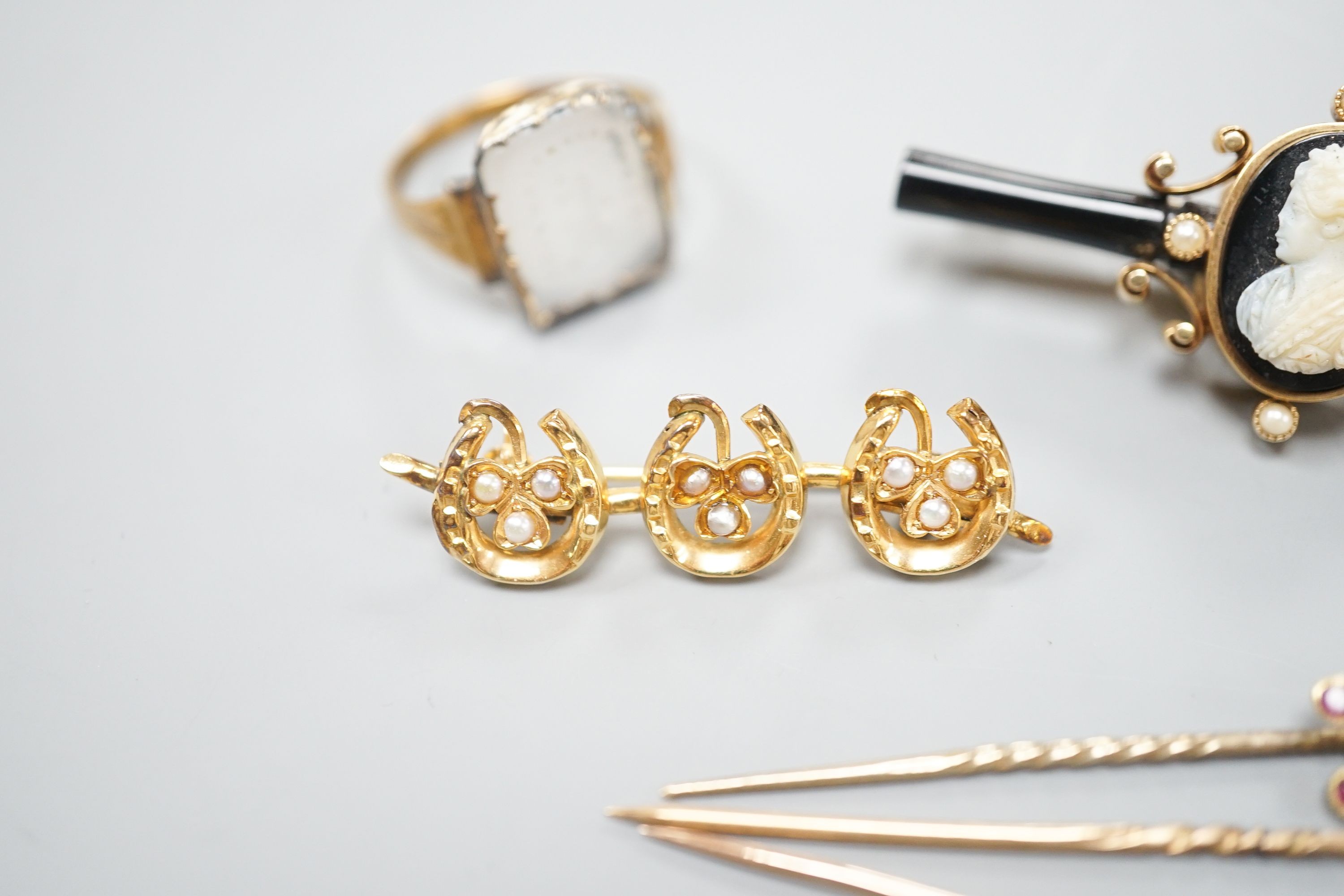 A 19th century yellow metal and white carnelian intaglio set ring, with crest and motto (a.f.), a yellow metal, sardonyx cameo, black onyx and seed pearl set bar brooch, 52mm, a Victorian gold triple horseshoe and seed p